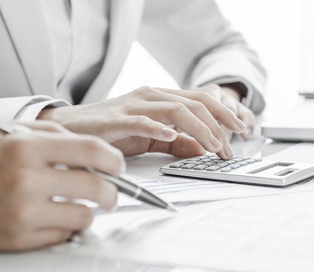 someone computing using a calculator and another writing down on a piece of paper